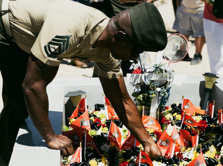 Gunnery Sgt. Reginald Berry, a branch chief with 3rd Light Armored Reconnaissance Battalion, 1st Marine Division, places flowers in the final resting place of Pfc. Michael A. Noline
