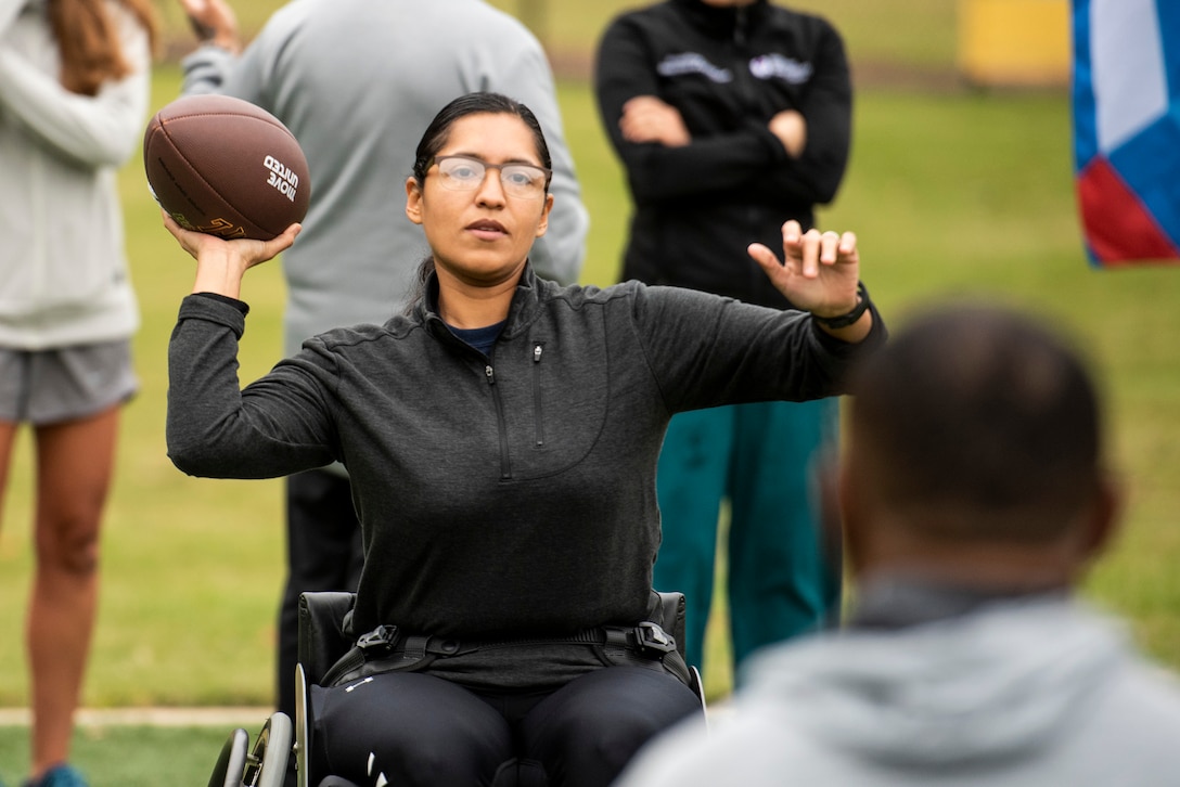 A recovering service member throws a ball to a fellow athlete while learning the skills of wheelchair football.
