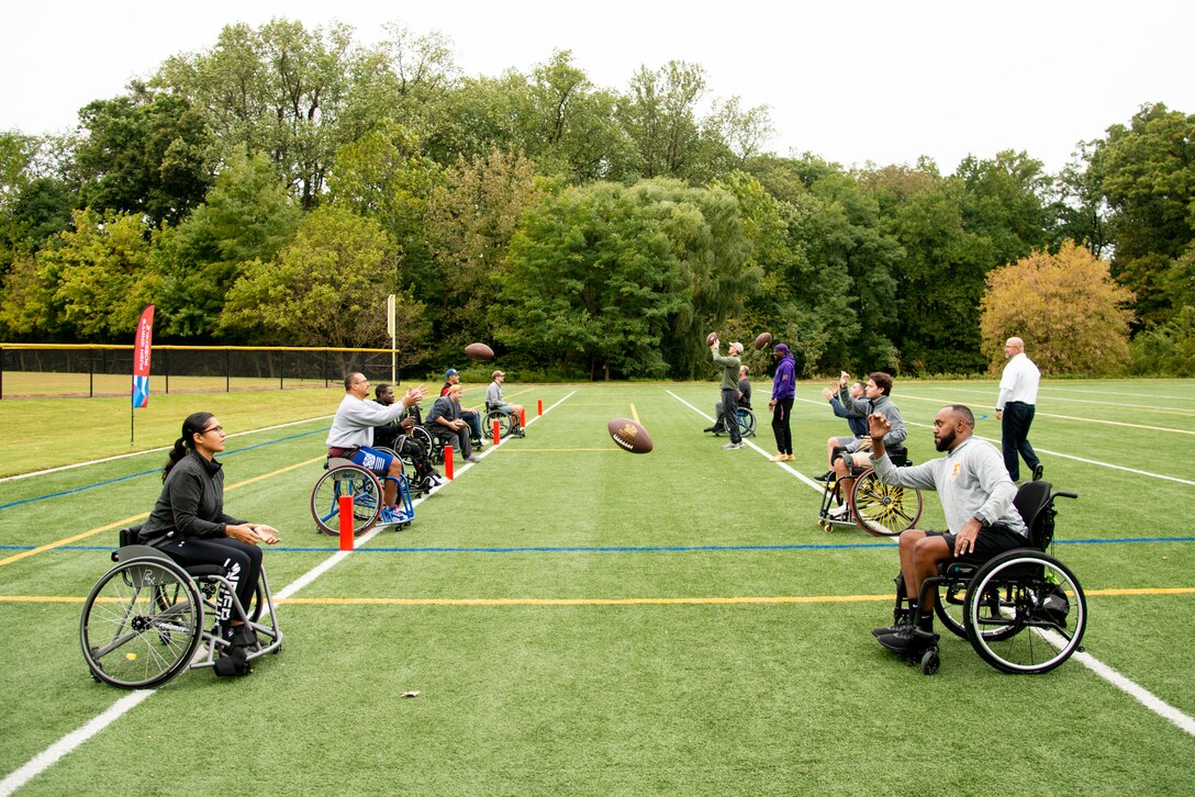 Athletes toss a ball back and forth as they learn skills necessary for wheelchair football.