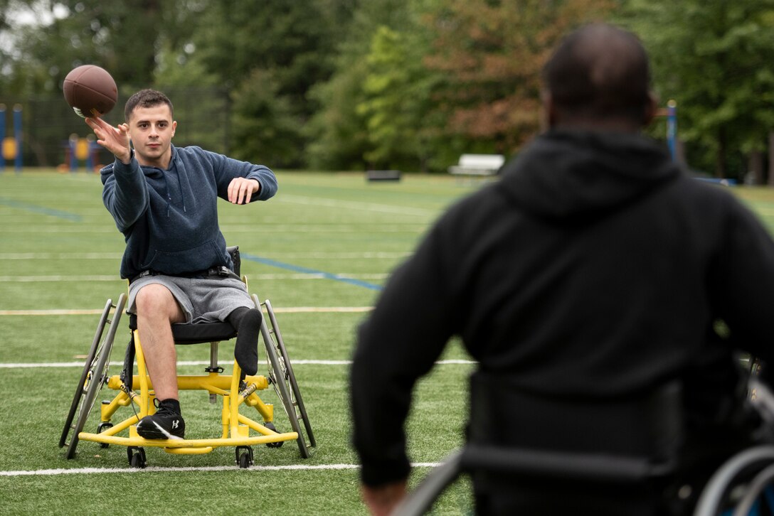 A recovering service member throws a football to a fellow athlete.