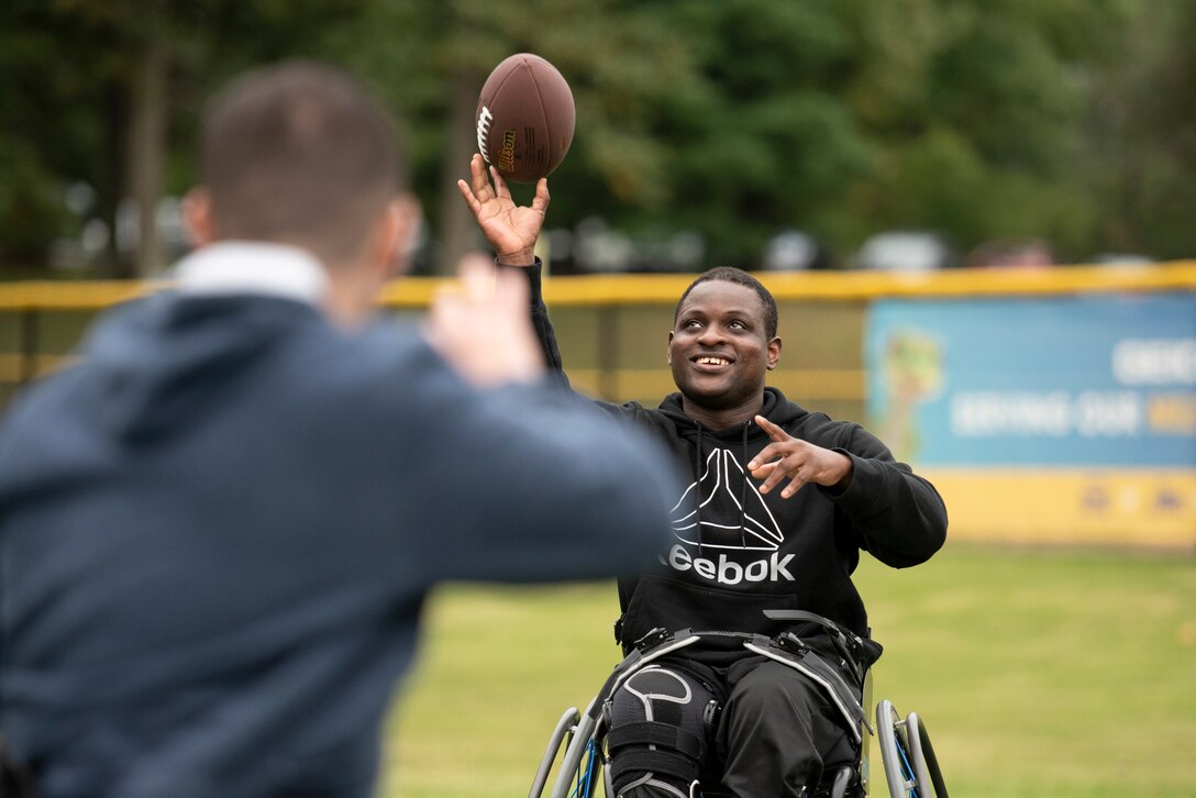 A recovering service member throws a football to a fellow athlete.