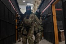 Airman in combat gear walk through a hallway.