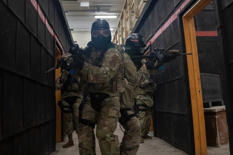 Airman in combat gear walk through a hallway.
