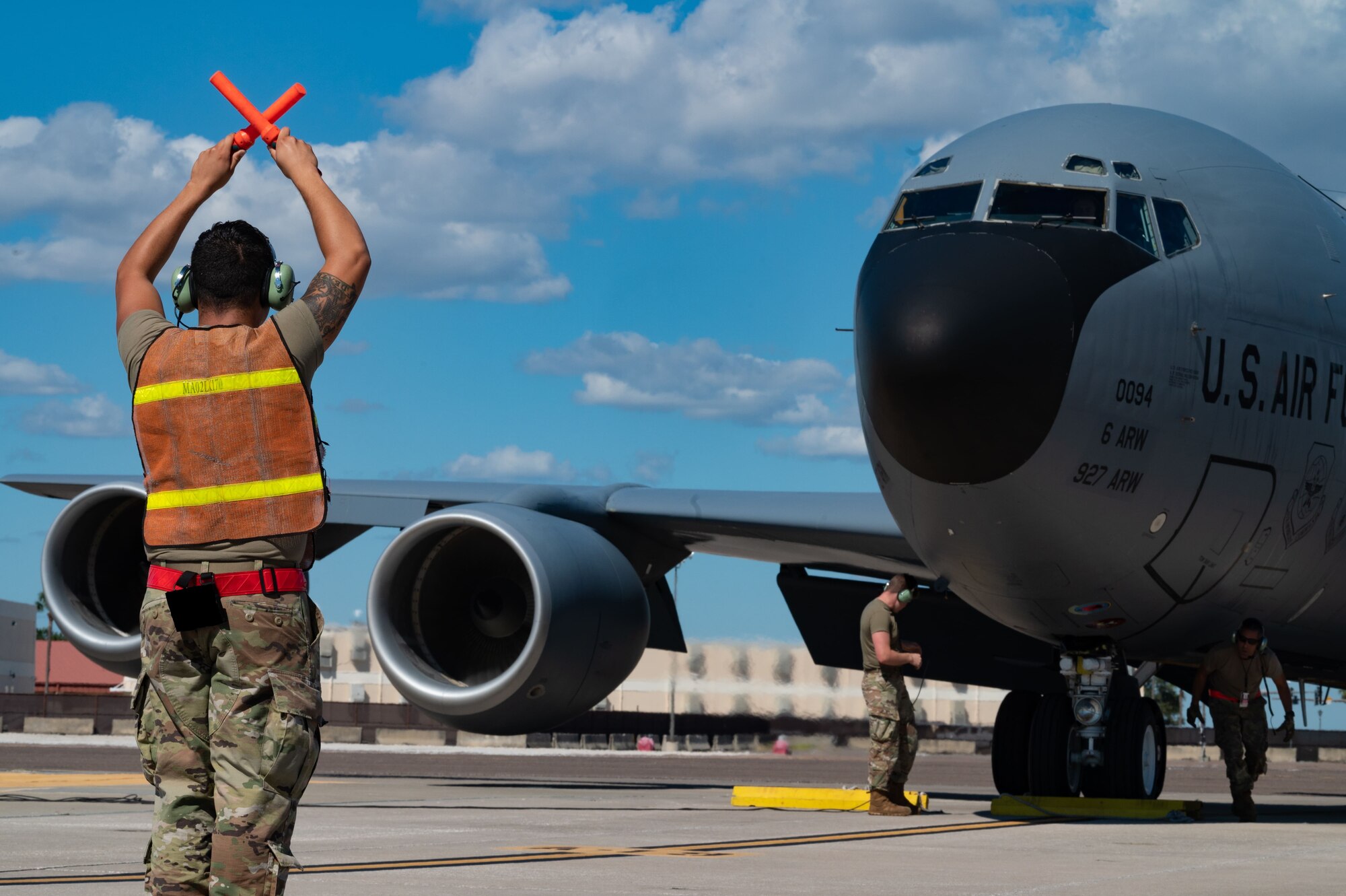 U.S. Air Force Airman 1st Class Francisco Garcia, a crew chief assigned to the 6th Aircraft Maintenance Squadron, guides a landing KC-135 Stratotanker