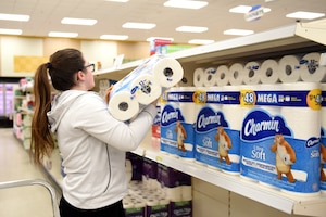 Commissary worker stocks toilet paper on the shelf