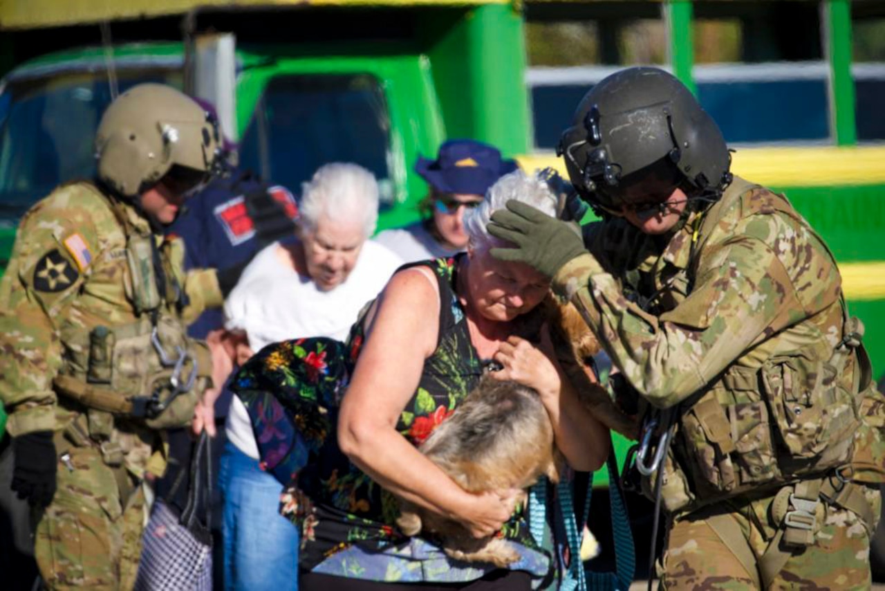 A guardsman shields a woman who is holding a dog; others stand behind.