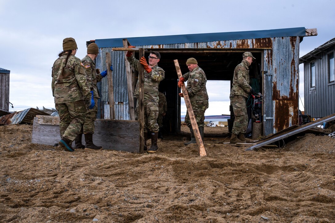 Alaska Air and Army National Guardsmen from Joint Task Force-Alaska rebuild the door of a small garage in Golovin, Alaska, Sept. 27, 2022. More than 130 members of the Alaska Organized Militia, which includes members of the Alaska National Guard, Alaska State Defense Force and Alaska Naval Militia, were activated following a disaster declaration issued Sept. 17 after the remnants of Typhoon Merbok caused dramatic flooding across more than 1,000 miles of Alaskan coastline. (Alaska National Guard photo by Pfc. Bradford Jackson)