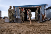 Alaska Air and Army National Guardsmen from Joint Task Force-Alaska rebuild the door of a small garage in Golovin, Alaska, Sept. 27, 2022. More than 130 members of the Alaska Organized Militia, which includes members of the Alaska National Guard, Alaska State Defense Force and Alaska Naval Militia, were activated following a disaster declaration issued Sept. 17 after the remnants of Typhoon Merbok caused dramatic flooding across more than 1,000 miles of Alaskan coastline. (Alaska National Guard photo by Pfc. Bradford Jackson)