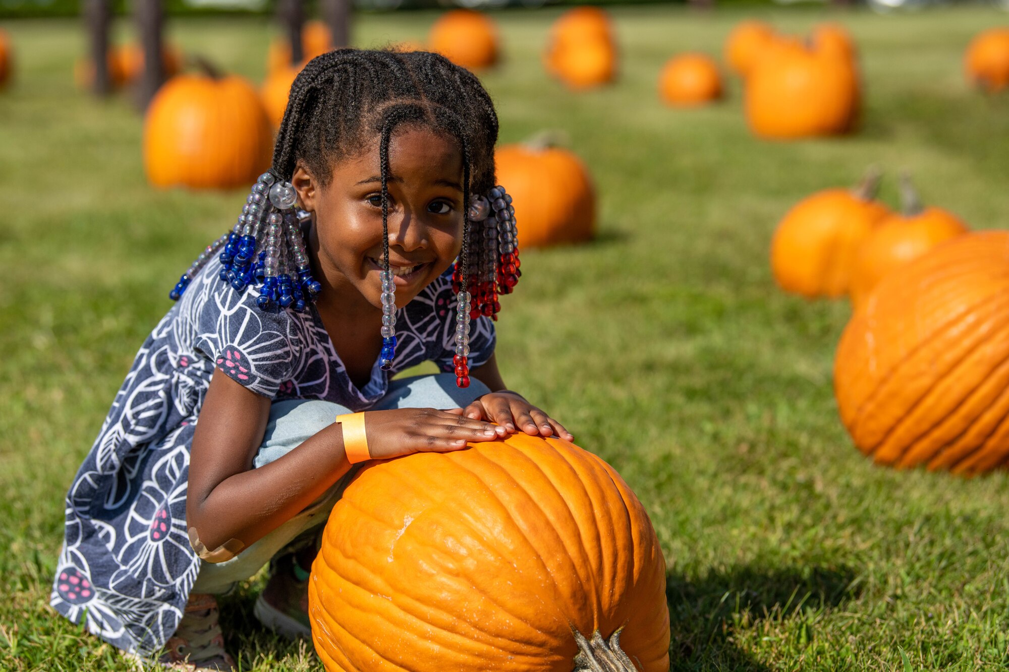 A little girl poses for a photo in a pumpkin patch