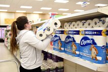 Commissary worker stocks toilet paper on the shelf