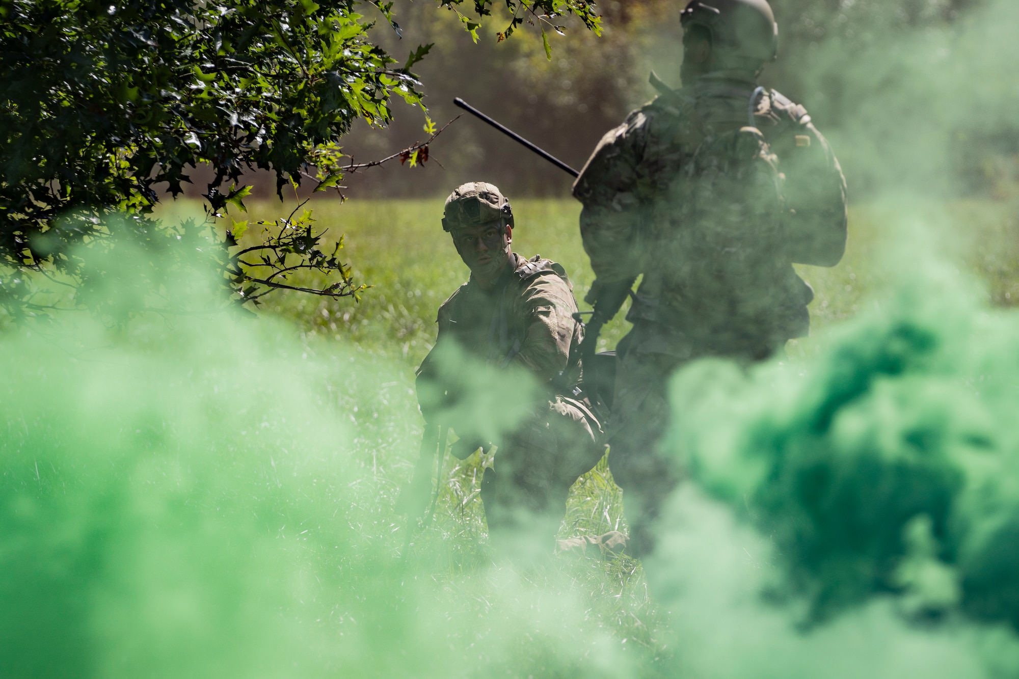 Airmen walk through a smog of green smoke clouds.
