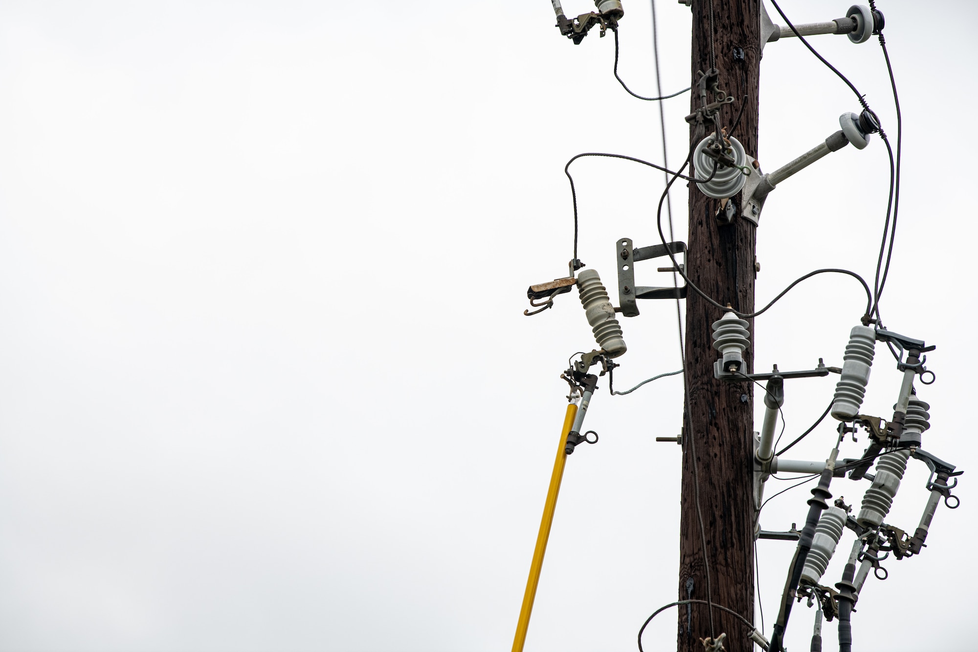 An Airman replaces a fuse on a power line