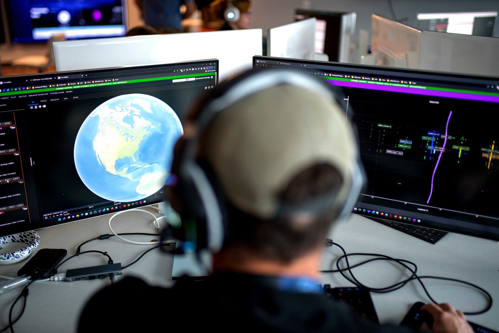 Back of a man's head looking at two computer screens