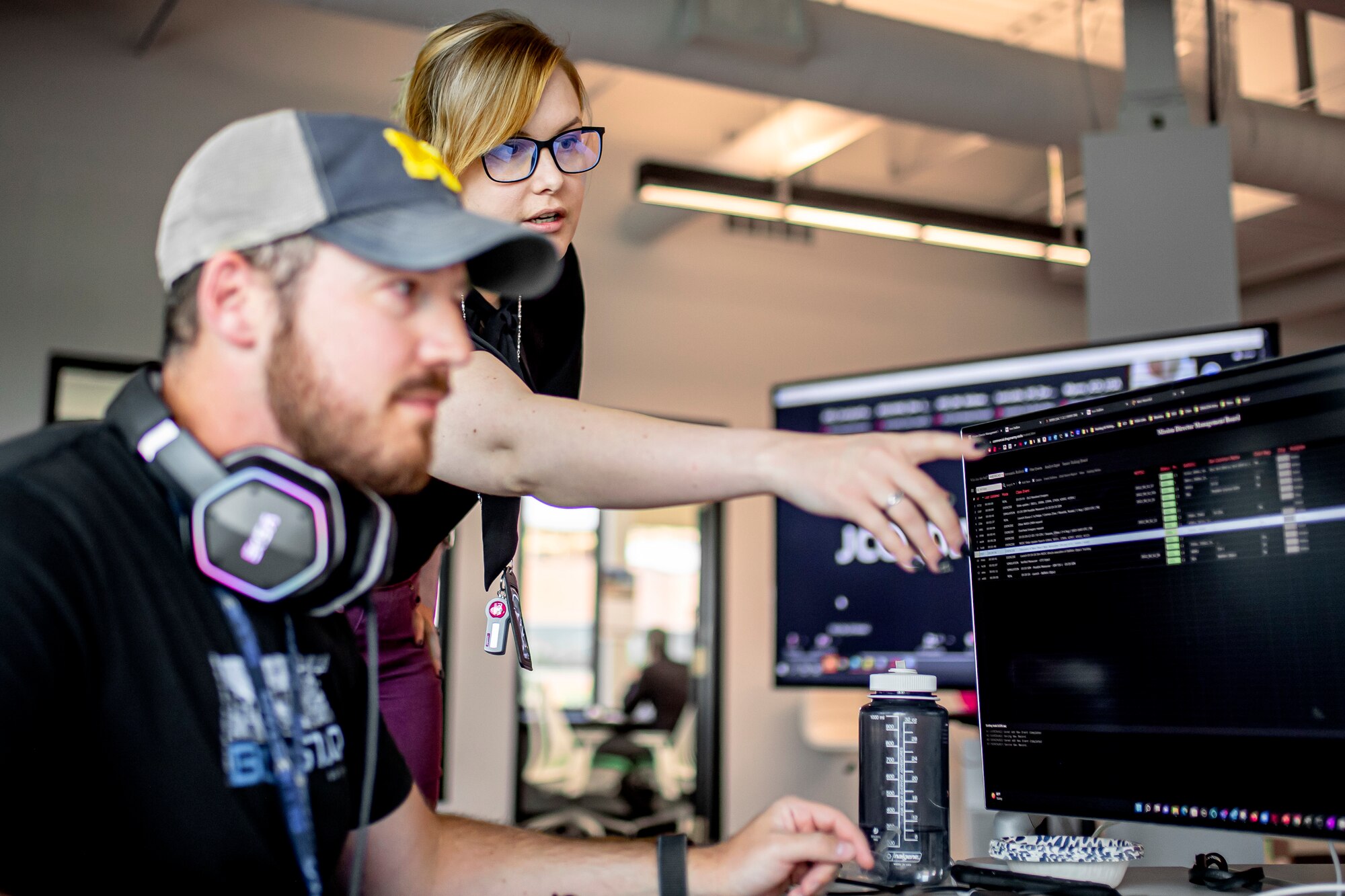 Man listening to woman pointing at a computer screen
