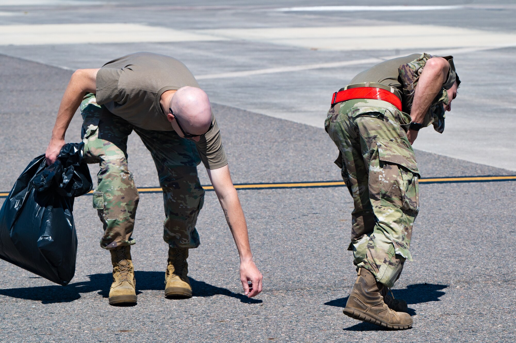 U.S. Airmen assigned to the 6th Maintenance Squadron pick up debris during a foreign object debris walk