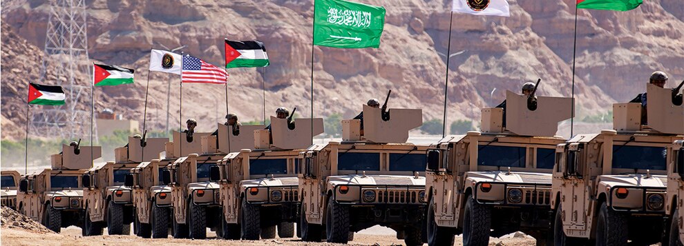 A parade of High Mobility Multipurpose Wheeled Vehicles with the Saudi Arabian flag, Jordanian flag, and U.S. flag enter the exercise area at the end of the Eager Lion 22 final exercise at the Royal Jordanian Naval Base, Jordan on September 11, 2022.
