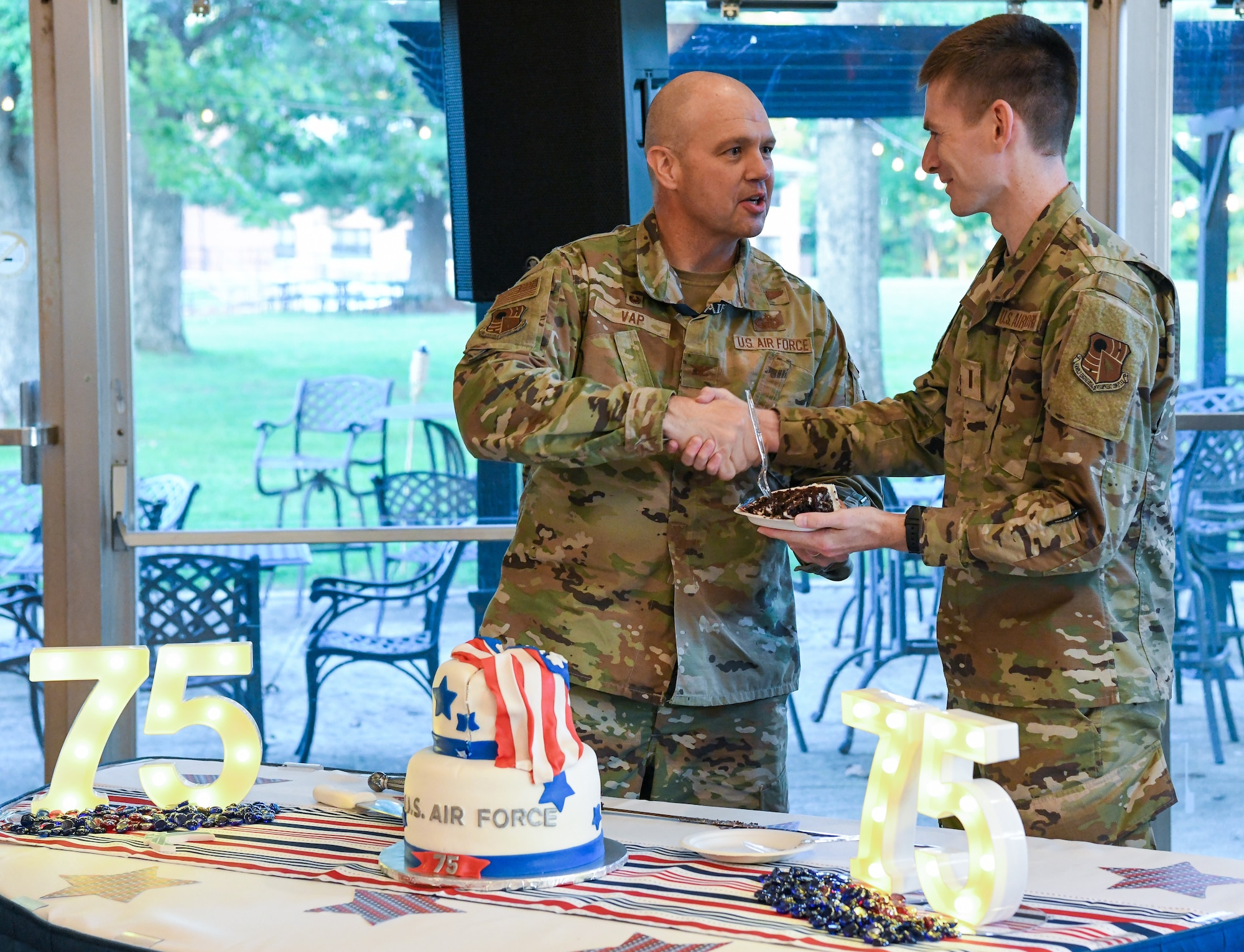 Airman shaking hands and serving cake to another Airman