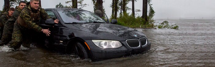 Marines with Marine Corps Base Camp Lejeune help push a car out of a flooded area during Hurricane Florence, on Marine Corps Base Camp Lejeune, Sept. 15, 2018. Hurricane Florence impacted MCB Camp Lejeune and Marine Corps Air Station New River with periods of strong winds, heavy rains, flooding of urban and low lying areas, flash floods and coastal storm surges. (U.S. Marine Corps photo by Lance Cpl. Isaiah Gomez). Cropped version of 180915-M-JQ384-009