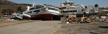 Two several-ton ferries, still attached to their concrete pier, sit on the road leading to the harbor. The ferries, along with their pier, were lifted and moved almost 100 yards inland by the massive tsunami that tore through the island March 11. Marines and sailors with 2nd Battalion, 5th Marine Regiment, from the 31st Marine Expeditionary Unit began clean-up efforts in support of the local citizens. Cropped version of 110401-M-QE984-172