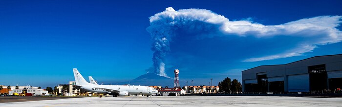210304-N-KT659-1005 NAVAL AIR STATION SIGONELLA, Italy (March 4, 2021) Two P-8A Poseidon maritime patrol aircraft assigned to Patrol squadron (VP) 46 sit on the flight line as Mount Etna erupts, March 4, 2021. VP-46 is currently forward-deployed to the U.S. Sixth Fleet area of operations and is assigned to Commander, Task Force 67, responsible for tactical control of deployed maritime patrol and reconnaissance squadrons throughout Europe and Africa. U.S. Sixth Fleet, headquartered in Naples, Italy, conducts a full spectrum of joint and naval operations, often in concert with allied and interagency partners, in order to advance U.S. national security interests and stability in Europe and Africa. (U.S. Navy photo by Mass Communication Specialist 3nd Class Zach Dalton/ Released) Cropped version of 210304-N-KT659-1005