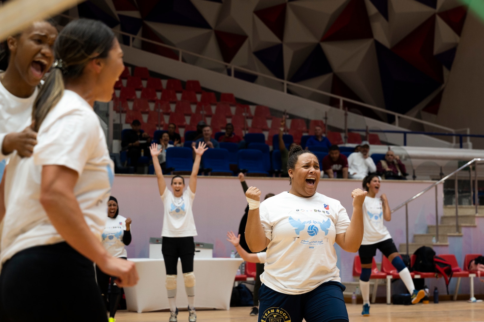 U.S. Air Force Staff Sgt. Ashley Mikaio, 386th Air Expeditionary Wing public affairs craftsman (center), celebrates alongside her team after a victory during the International Day of Peace volleyball tournament at the Kuwait Sports Club, Kuwait, October 1, 2022. U.S. Airmen, Soldiers and Kuwait volleyball players came together to play in all-female coalition teams in an exhibition of women’s strength and empowerment. (U.S. Air Force photo by Staff Sgt. Dalton Williams)