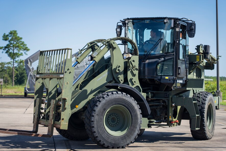 An Airman drives a forklift on pavement.