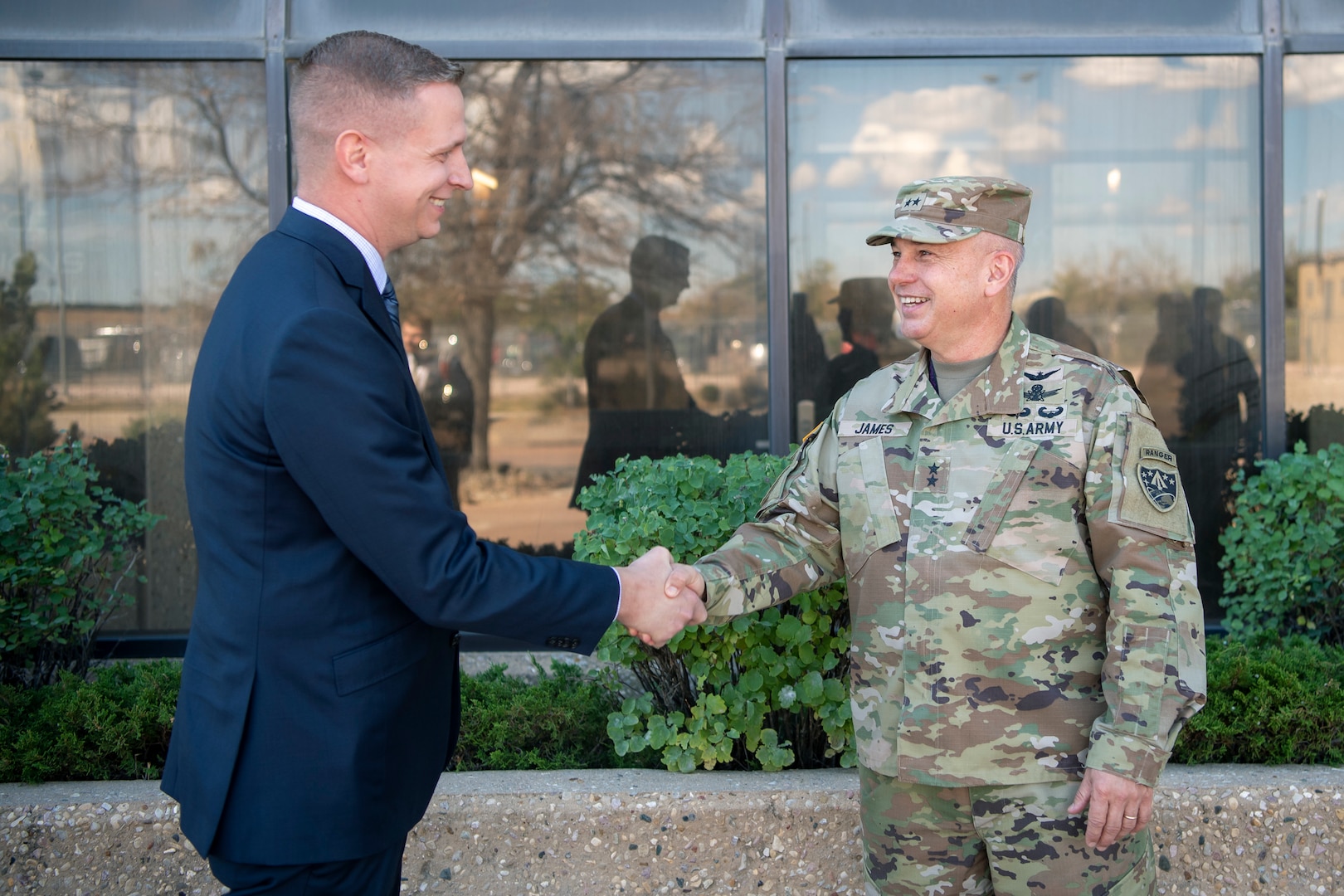 Man in suit shakes hands with man in Army uniform