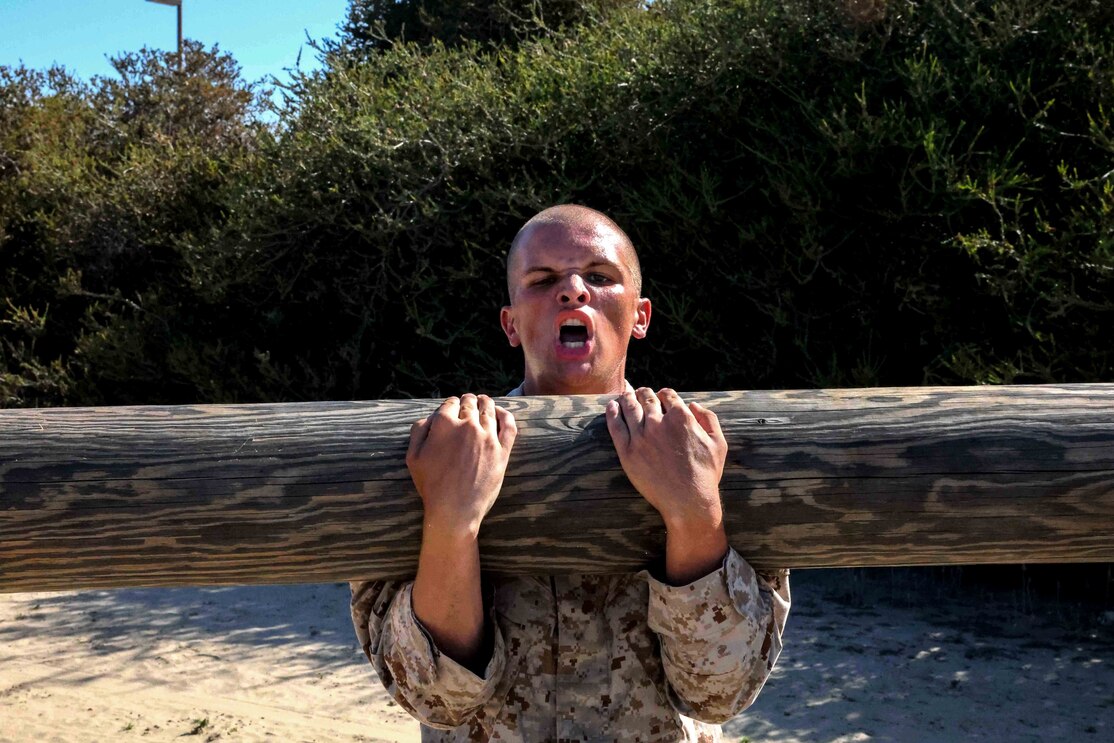 U.S. Marine Corps Recruit Jonathan Parks with Mike Company, 3rd Recruit Training Battalion, conducts team bicep curls during a log drill exercise at Marine Corps Recruit Depot San Diego, Sept. 26, 2022.