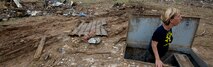 Christie England, an acquisition law paralegal with the 72nd Air Base Wing, Tinker Air Force Base, Okla., stands in her storm shelter in front of the remains of her home in Moore, Okla., May 27, 2013. England's home was destroyed in the May 20 EF-5 tornado that ripped through Moore. The storm killed 24, injured hundreds and damaged thousands of homes. England is from Olathe, Kan. (U.S. Air Force photo by Tech. Sgt. Bradley C. Church) Cropped version of 130527-F-IE715-189