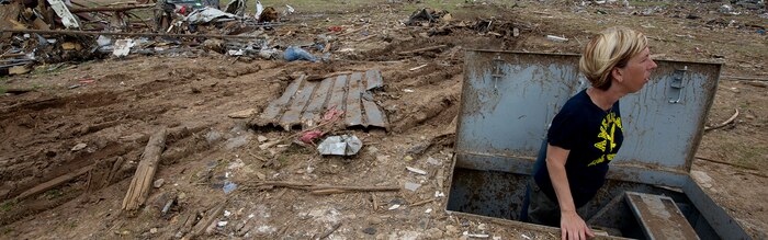 Christie England, an acquisition law paralegal with the 72nd Air Base Wing, Tinker Air Force Base, Okla., stands in her storm shelter in front of the remains of her home in Moore, Okla., May 27, 2013. England's home was destroyed in the May 20 EF-5 tornado that ripped through Moore. The storm killed 24, injured hundreds and damaged thousands of homes. England is from Olathe, Kan. (U.S. Air Force photo by Tech. Sgt. Bradley C. Church) Cropped version of 130527-F-IE715-189