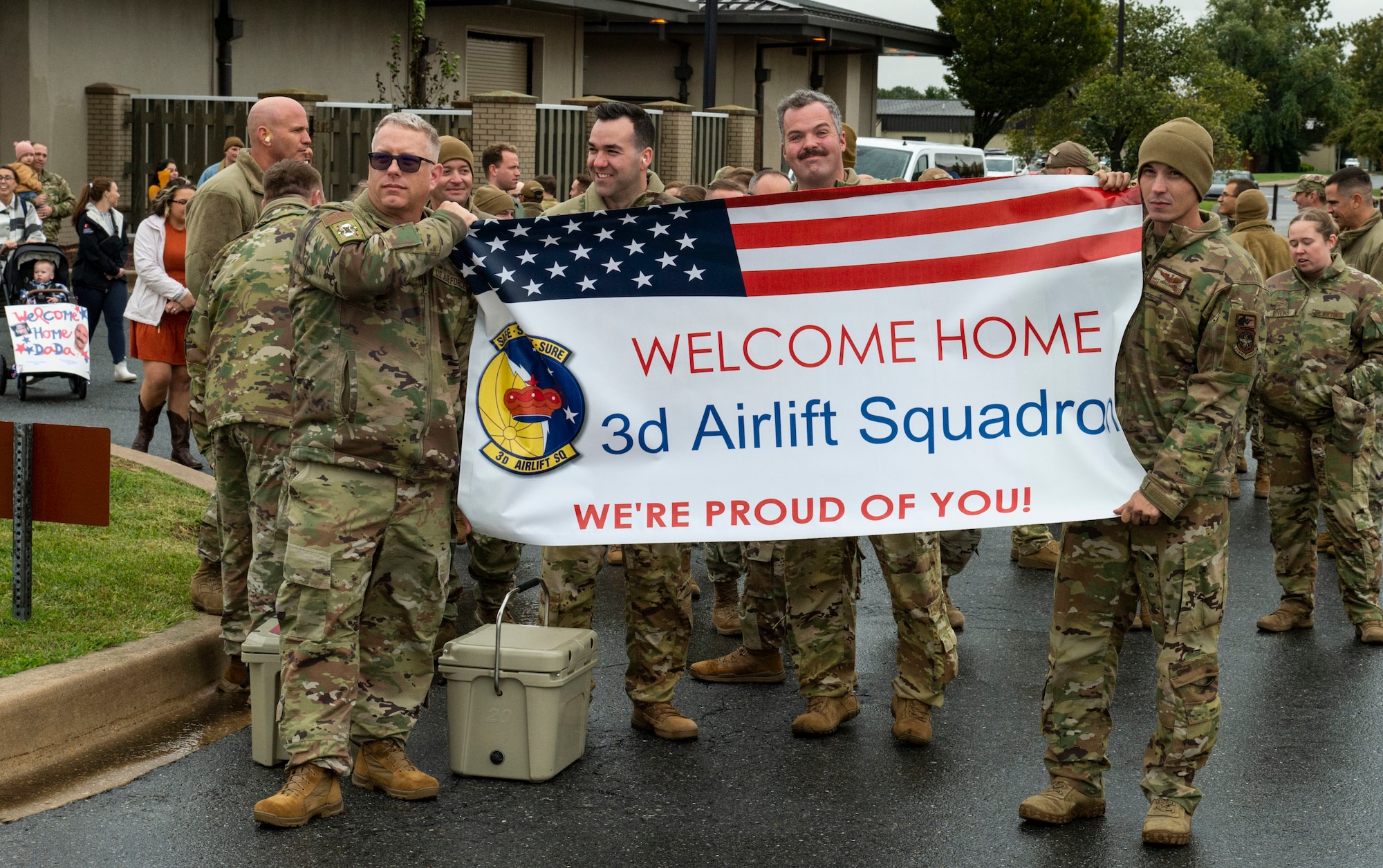 Members from the 3rd Airlift Squadron hold up a welcome home banner for fellow squadron members returning to Dover Air Force Base, Delaware, Oct. 3, 2022. Deployed Team Dover members returned to Dover after being deployed to Al Udeid Air Base, Qatar. The C-17 Globemaster III, operated by 3AS, is capable of rapid strategic delivery of troops and all types of cargo to main operating bases or directly to forward bases in a deployment area. (U.S. Air Force photo by Roland Balik)