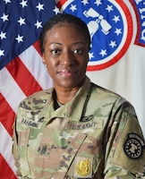 photo of women in u.s. army uniform standing in front of two flags.