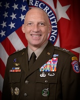 man wearing u.s. army uniform standing in front of two flags.
