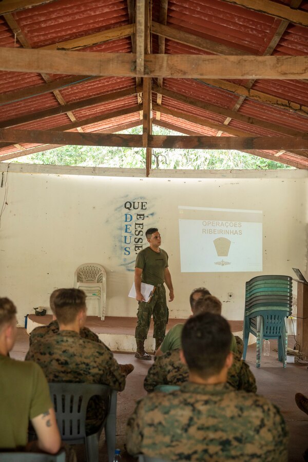 U.S. Marines and Sailors with 2d Battalion, 2d Marine Regiment, 2d Marine Division, listen as a Brazilian Marine instructs a riverine operations class as part of a bilateral jungle training event in Manaus, Brazil, Sept. 26, 2022. The Amazon jungle has significant waterways and littoral environments, the Brazilian Marines shared their vast knowledge and experience from operating along these rivers regularly. U.S. partnerships in the U.S. Southern Command area of responsibly are forged by shared challenges and common objectives. Bilateral training events such as jungle training develops and sustains relationships that improve the capacity of U.S. and partner nation maritime forces to achieve common desired effects. This exchange of knowledge between critical regional partners fosters interoperability, friendly relationships, and mutual cooperation. (U.S. Marine Corps photo by Sgt. Camila Melendez)