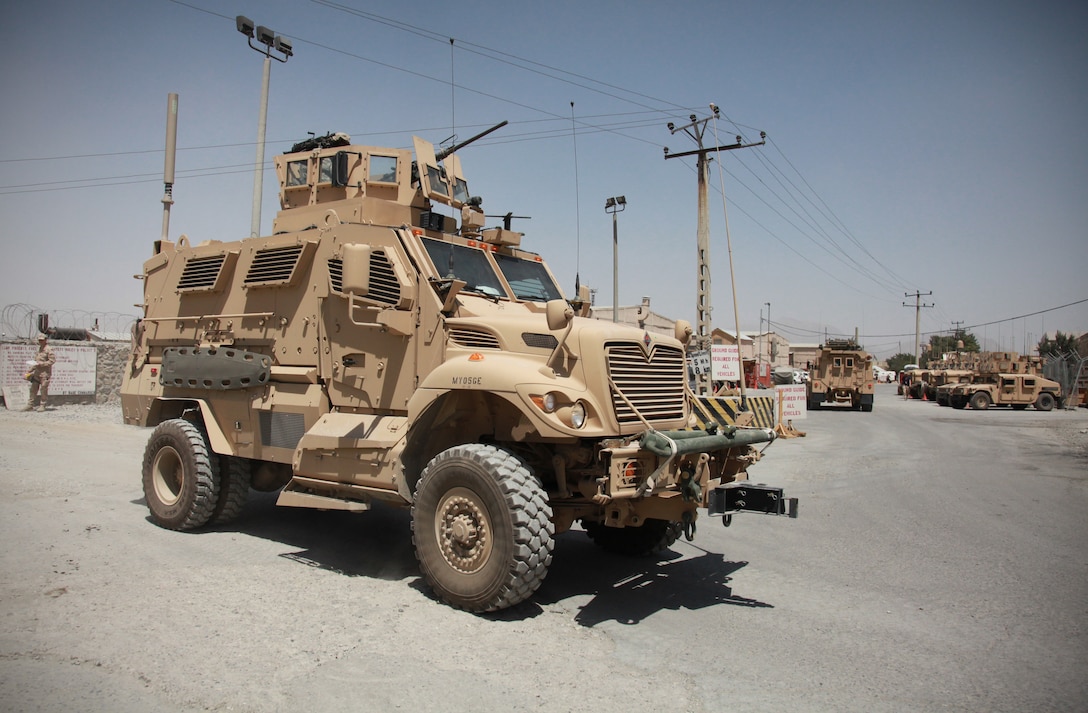 A large combat vehicle sits on a gravel lot.