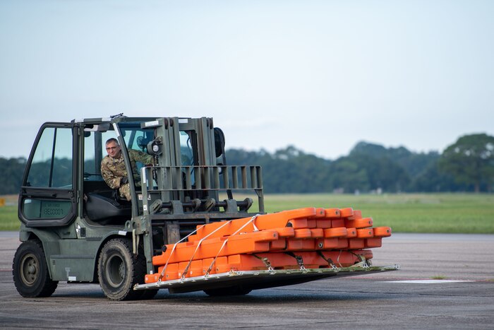 Callais sits in a forklift carrying plastic orange pieces