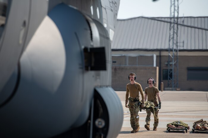 Two Airmen carry a litter onto an aircraft