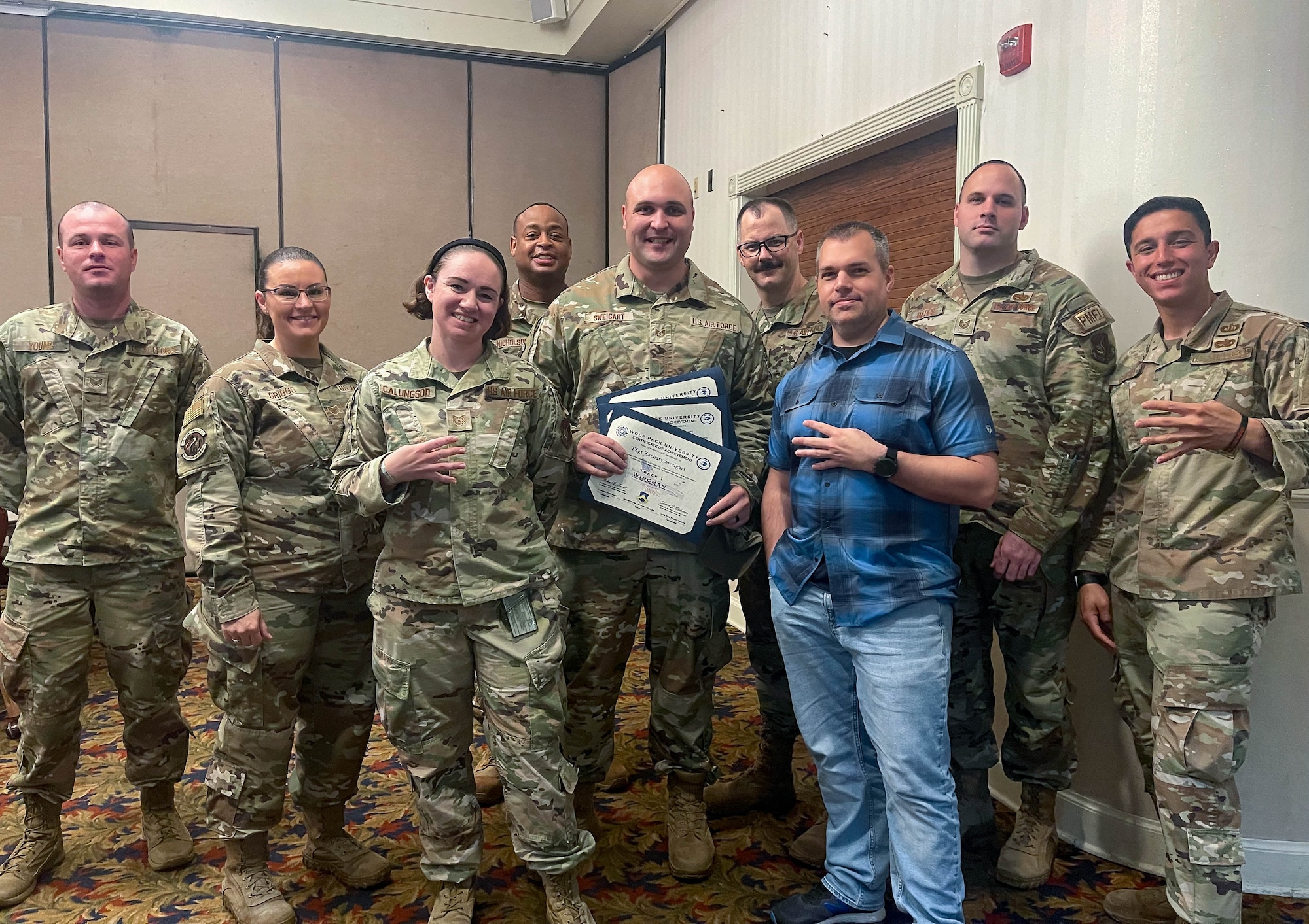 Airmen pose for a photo while holding a certificate.