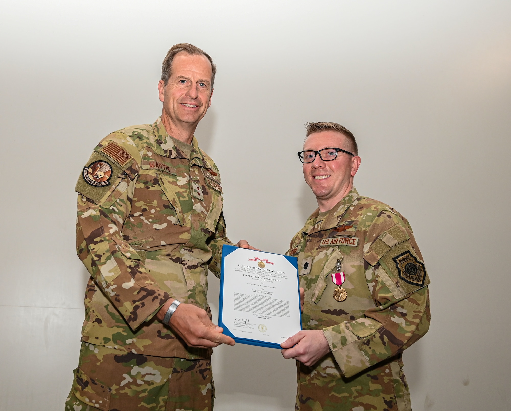 U.S. Air Force Maj. Gen. Corey Martin, 18th Air Force Commander (left), presents the Meritorious Service Medal to Lt. Col. Daniel Naske (right), 816th Expeditionary Airlift Squadron Commander, during an inactivation ceremony Sept. 30, 2022 at Al Udeid Air Base, Qatar. Martin was the presiding official for the ceremony, which marked 16 years of the squadron’s presence in Southeast Asia.  (U.S. Air National Guard photo by Master Sgt. Michael J. Kelly)