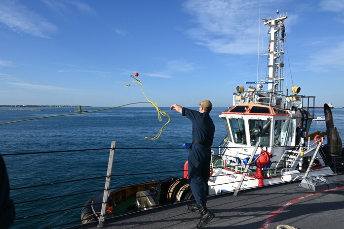 Information Systems Technician 3rd Class Lars Petelle throws the heaving line in preparation for making up a tug during a sea and anchor evolution into Taranto, Italy aboard Arleigh Burke-class guided missile destroyer USS Forrest Sherman (DDG 98).