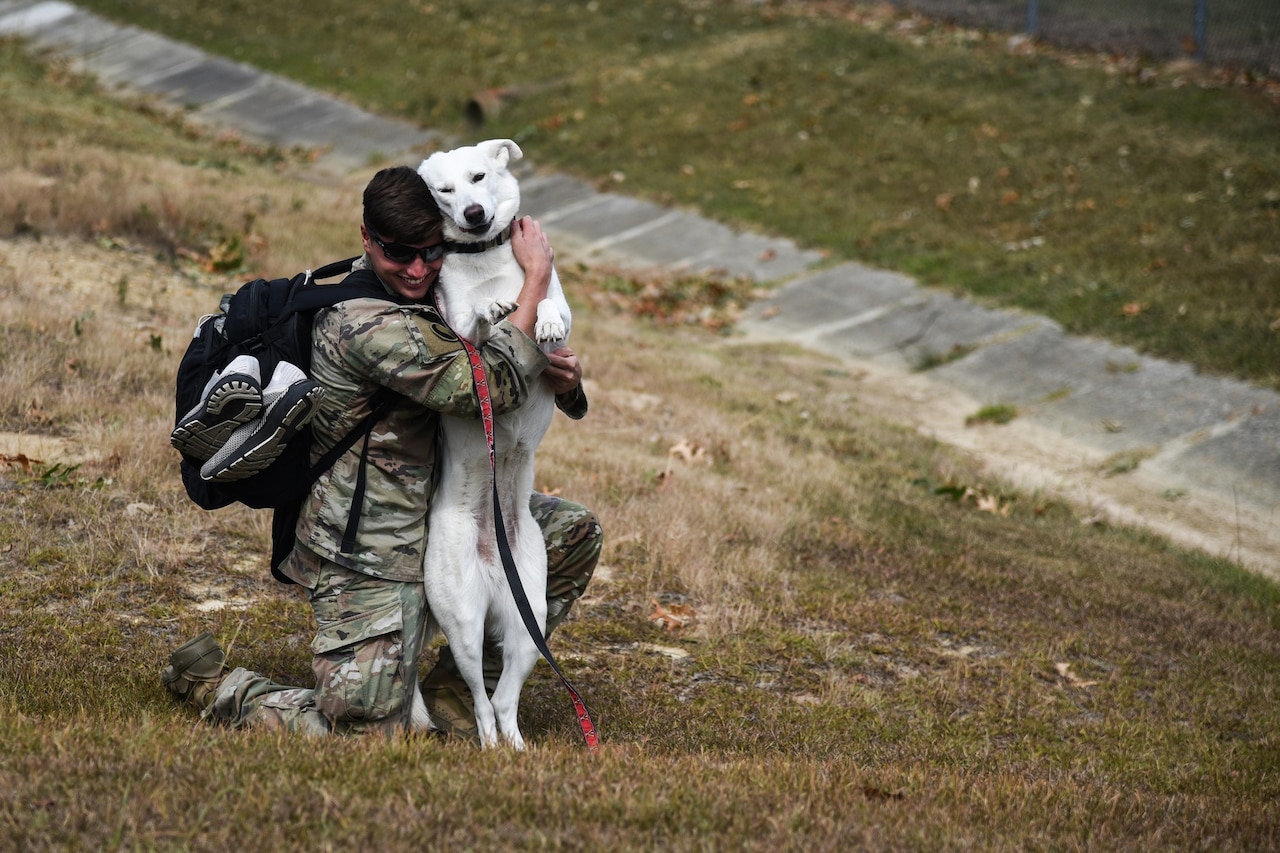 A soldier gives a dog a big hug.