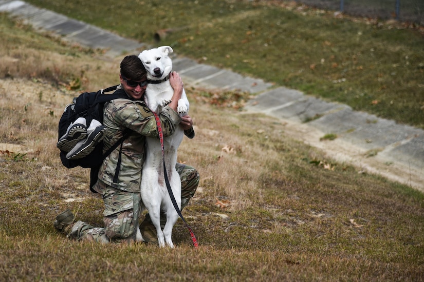 A soldier gives a dog a big hug.