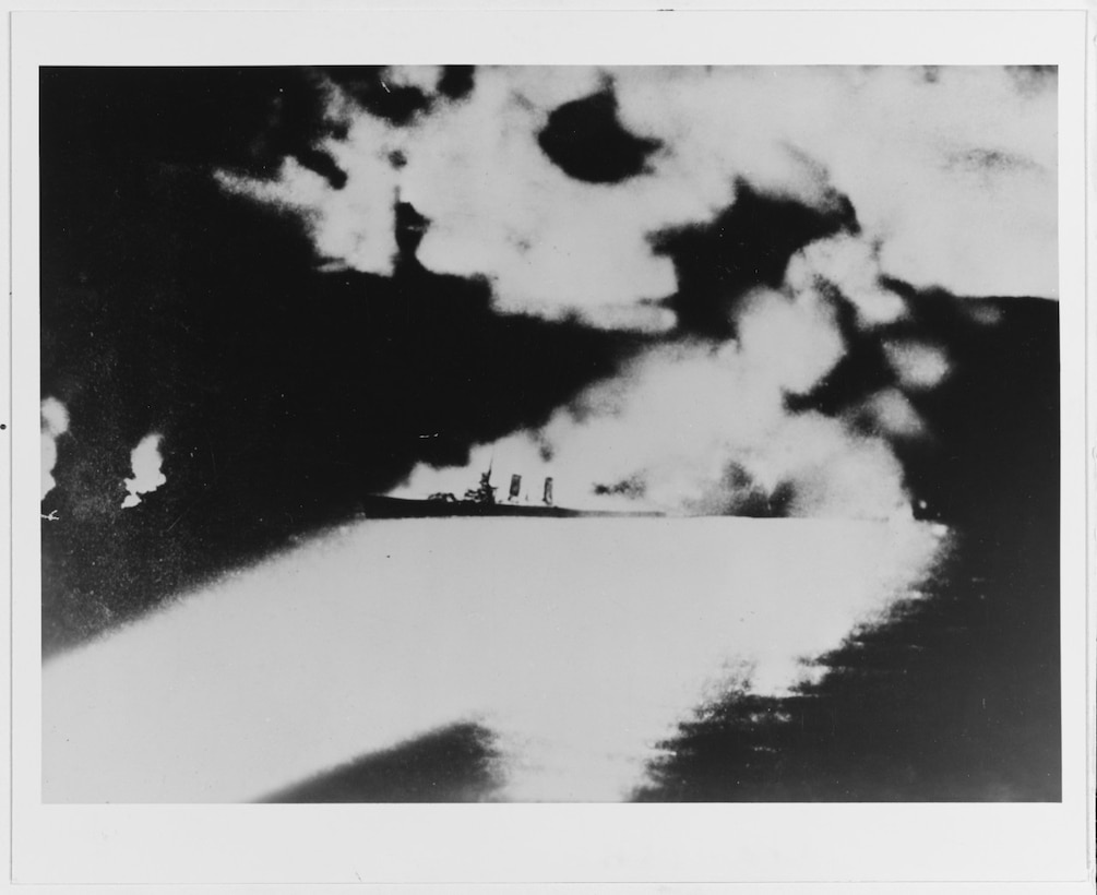 USS Quincy (CA-39) photographed from a Japanese cruiser during the Battle of Savo Island, off Guadalcanal, 9 August 1942. Quincy, seen here burning and illuminated by Imperial Japanese searchlights, was sunk in this action (NH 50346).