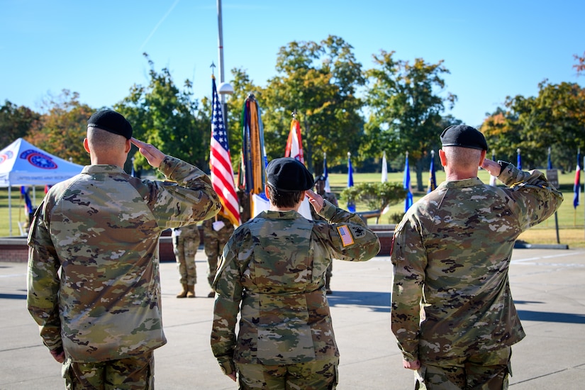 three people wearing u.s. army uniforms salute the flag