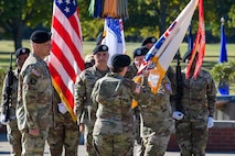 man wearing u.s. army uniform passes flag to woman wearing u.s. army uniform