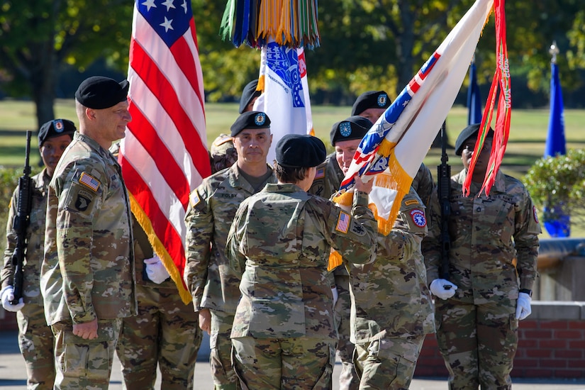 man wearing u.s. army uniform passes flag to woman wearing u.s. army uniform