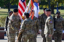 woman wearing u.s. army uniform passes flag to man wearing u.s. army uniform