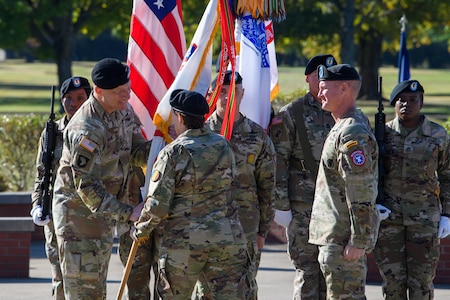 woman wearing u.s. army uniform passes flag to man wearing u.s. army uniform