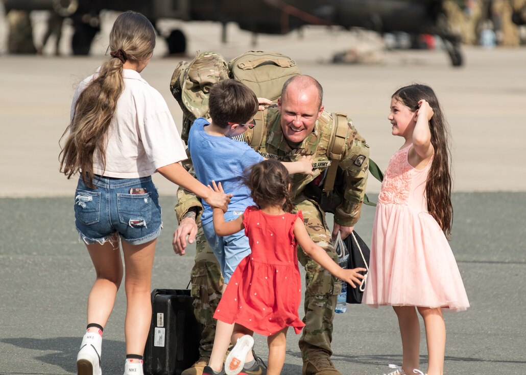 A Soldier assigned to the 1st Battalion, 3rd Aviation Regiment "Viper Battalion," 12th Combat Aviation Brigade embraces his family at the Katterbach Army Airfield, Germany, May 13, 2022. The Soldiers initially deployed to the Baltic region for a training exercise and remained forward to support Operation Assure, Deter, and Reinforce. 12 CAB is among other units assigned to V Corps, America's Forward Deployed Corps in Europe. They work alongside NATO Allies and regional security partners to provide combat-ready forces, execute joint and multinational training exercises, and retain command and control for all rotational and assigned units in the European Theater. (U.S. Army photo by Staff Sgt. Thomas Mort)