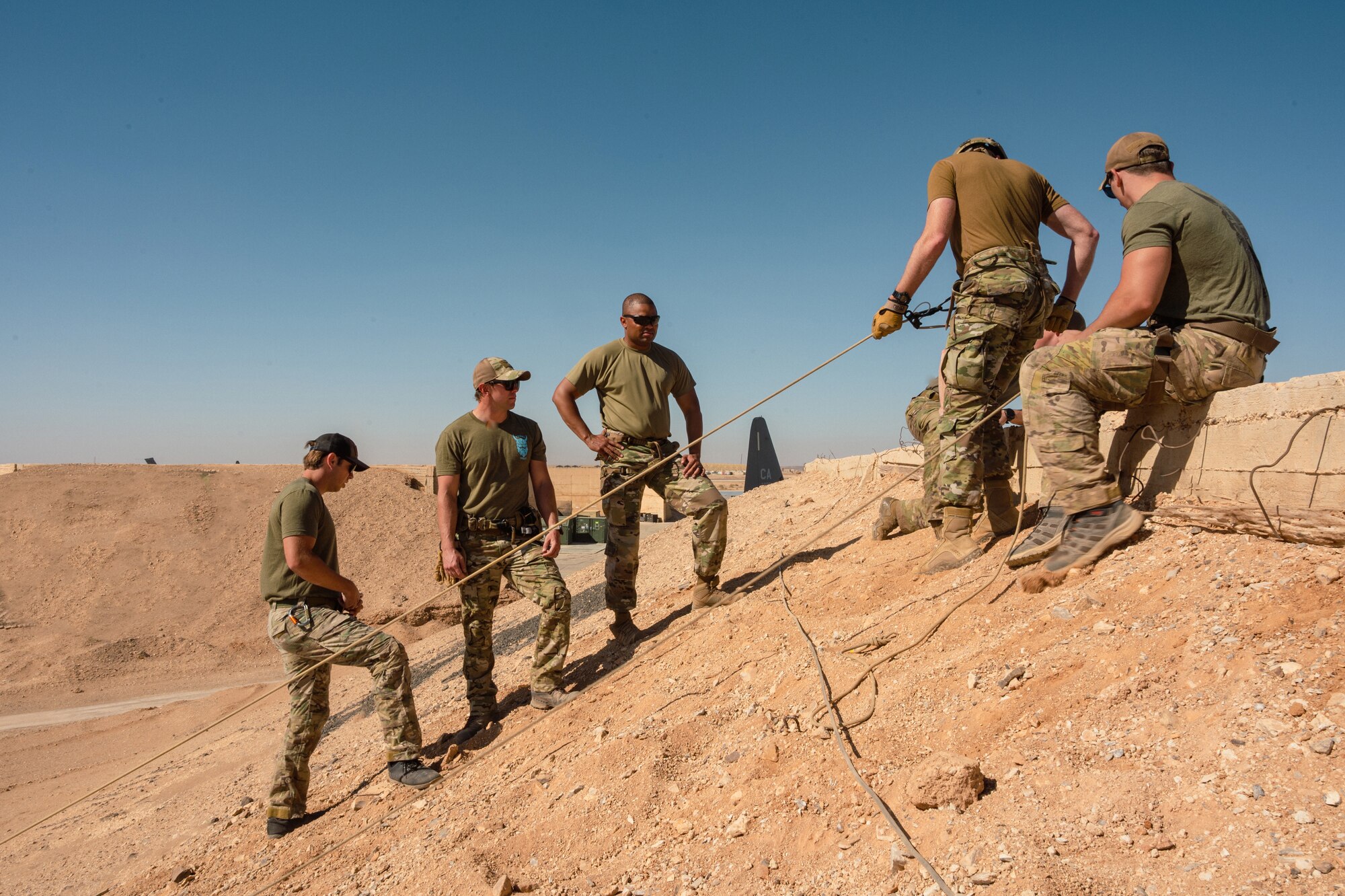 U.S. Air Force Personnel Recovery Task Force members assigned to the 52nd Expeditionary Rescue Squadron, instruct U.S. Air Force Col. Jason Houston, Deputy Wing Commander, 332d Air Expeditionary Wing, on an anchor line system for a technical rescue and rappel operation, as part of the “Red Tail Connection” program at an undisclosed location, September 28, 2022. These immersion visits provide greater insight into the unique skillsets every Airman brings to the 332d AEW Red Tail team. (U.S. Air Force photo by Tech. Sgt. Richard Mekkri)